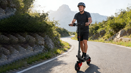 Person riding an electric scooter on a scenic road with mountains in the background